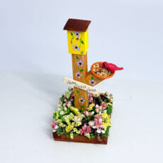 Yellow Bird House on Post with Flowers